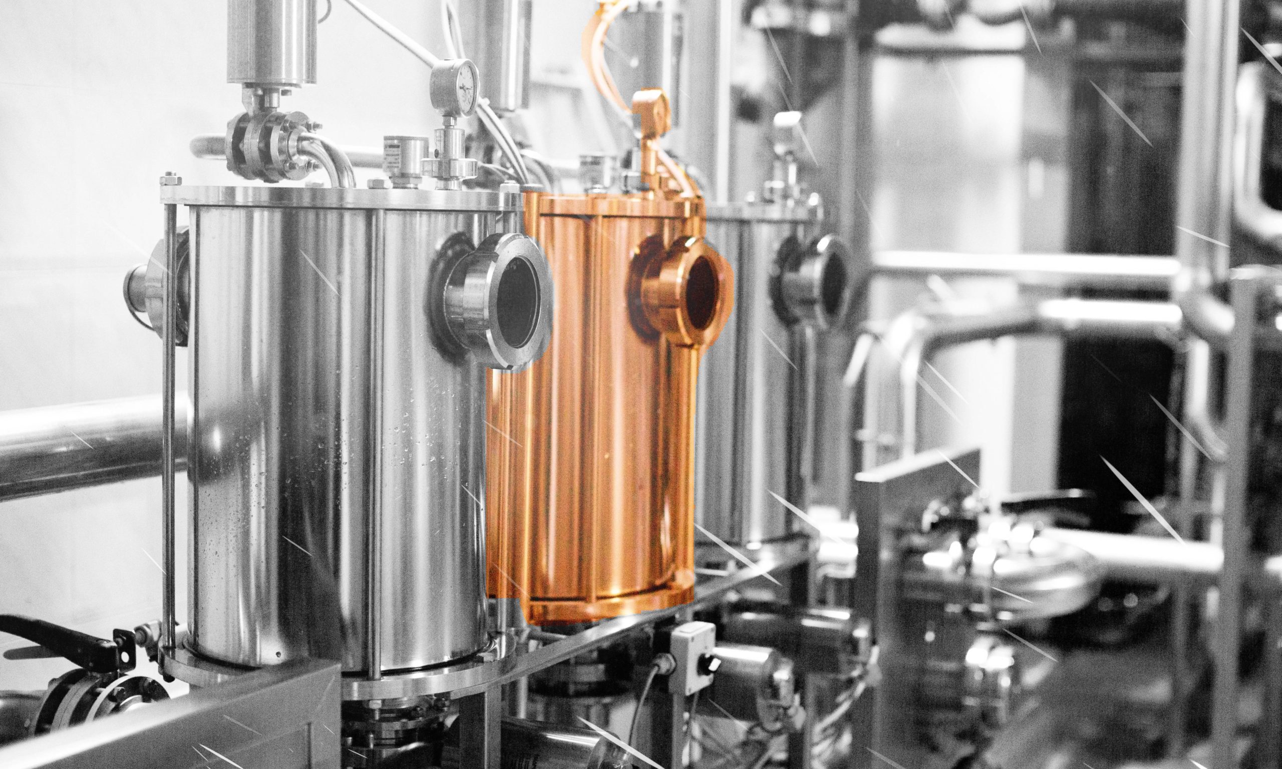 A distillery in with 3 copper pot stills in black and white. The second pot still is fully colored in copper.
