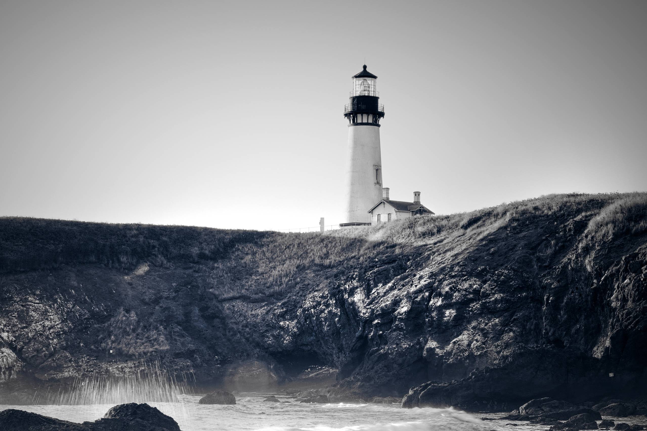 A light house stands guard on a rocky coast.