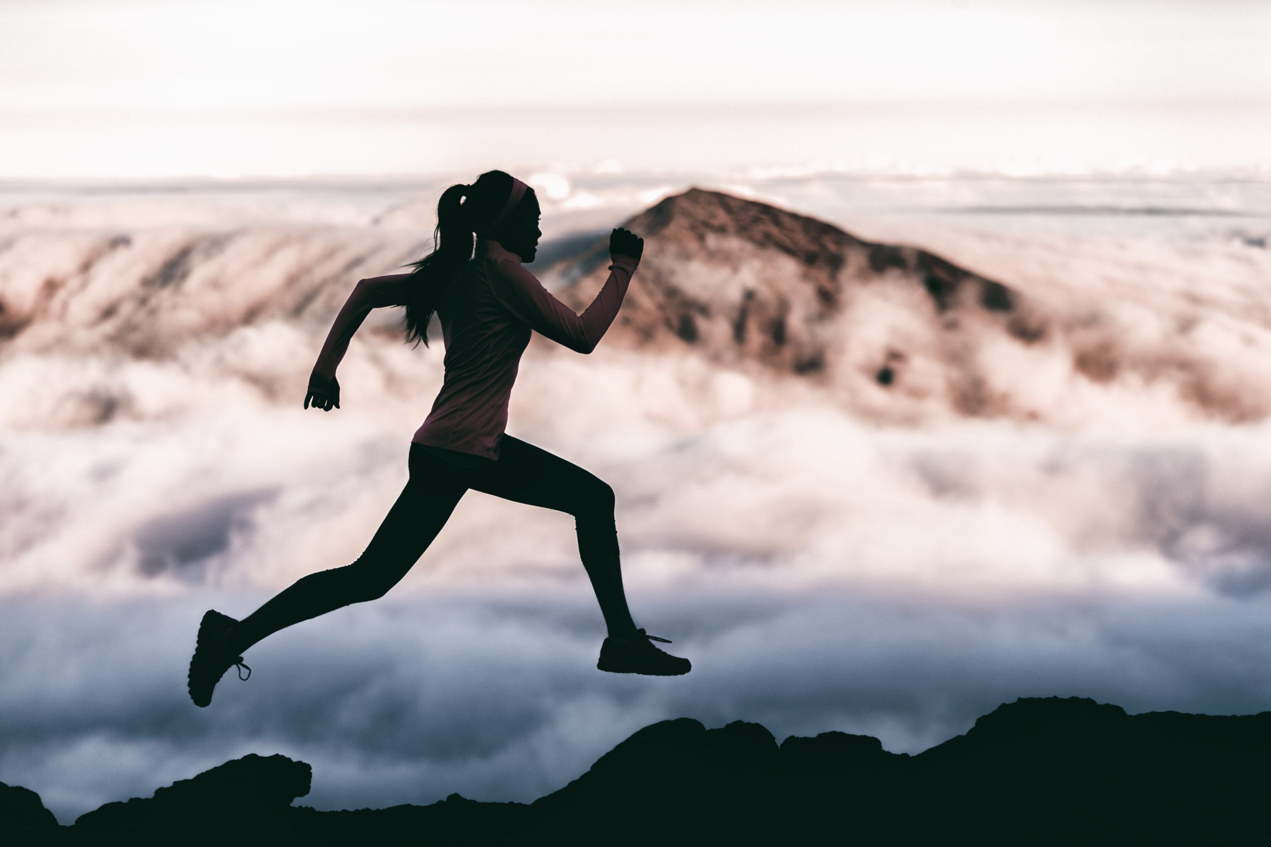 A woman runs at peak performance through the mountain tops.